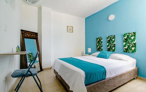 a blue bedroom with a bed and a chair at La Mochila SM in Santa Marta
