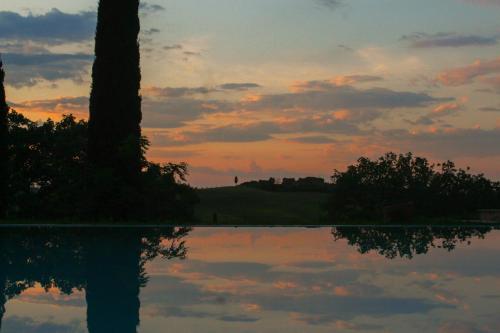 a sunset with a reflection in a body of water at Agriturismo Quarantallina in Buonconvento