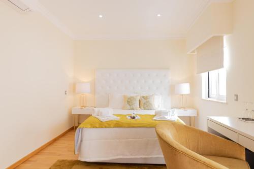 a white bedroom with a bed and two chairs at Sunny, The House - AL in Faro
