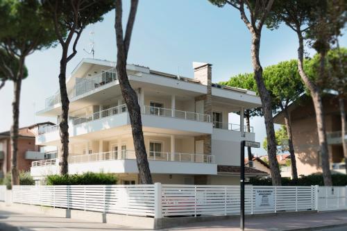 a white building with trees in front of it at Casa Baroncini Appartamenti in Cervia