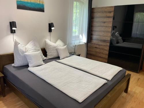 uma cama com lençóis brancos e almofadas num quarto em Marina Apartman em Siófok