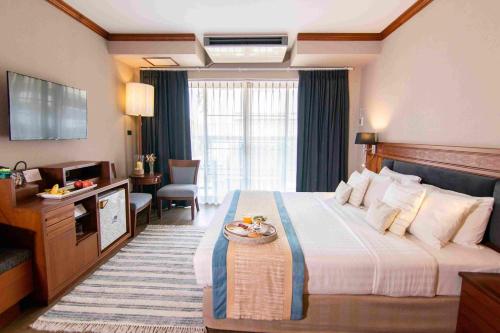 um quarto de hotel com uma cama grande e uma televisão em Tohsang Heritage Ubon Ratchathani Hotel em Ubon Ratchathani