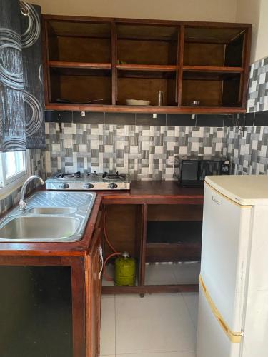 a kitchen with a sink and a refrigerator at Gloton apartments in Sere Kunda