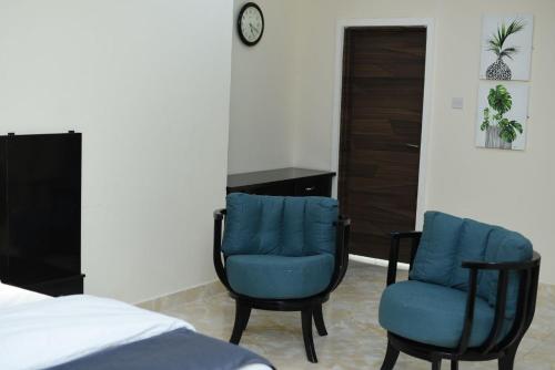 a bedroom with two blue chairs and a bed at Abi's Place in Tungan Ali
