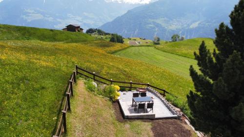 Alpenglück في فيس: طاولة وكراسي على تلة مع جبال في الخلفية