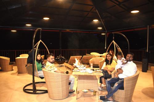 a group of people sitting around a table on a stage at Captains Paradise Luxury Resort at Mukteshwar Hill Station in Mukteswar