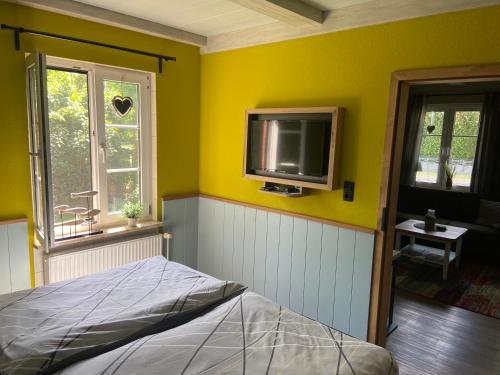 a bedroom with yellow walls and a tv on the wall at Lütte Uttiet in Stelle-Wittenwurth