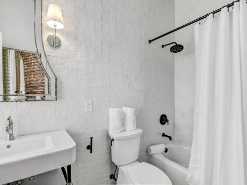 a white bathroom with a toilet and a sink at Gordon Inn Tree Top in Savannah