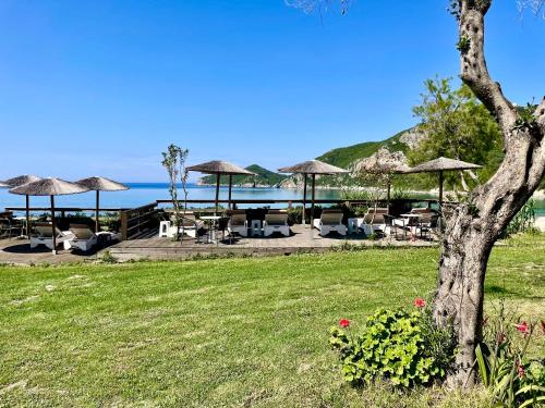 a patio with tables and umbrellas and the ocean at Hamre Apartments (Nicholas) in Agios Georgios Pagon