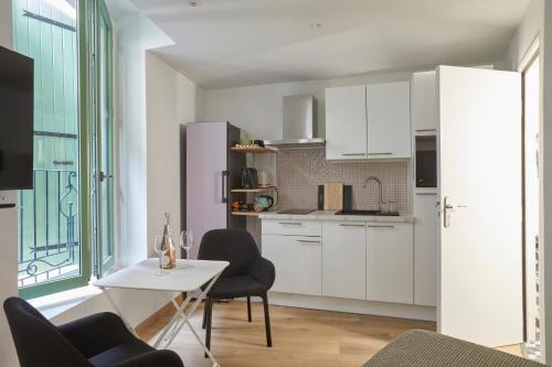 une cuisine avec des armoires blanches et une table et des chaises dans l'établissement Art Lovers Apart First Floor, à Béziers