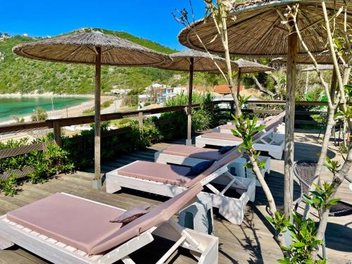 a group of lounge chairs and umbrellas on a deck at Hamre Apartments (Nicholas) in Agios Georgios Pagon