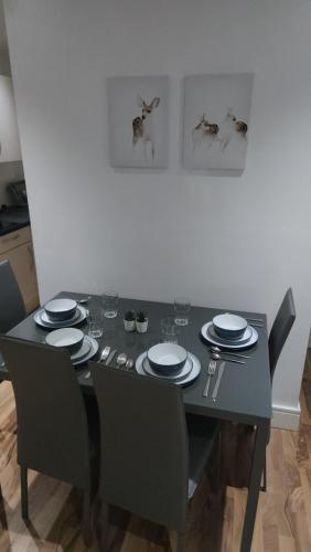 - une table à manger avec des chaises et des assiettes dans l'établissement City Sparrow Apartment 3, à Londres