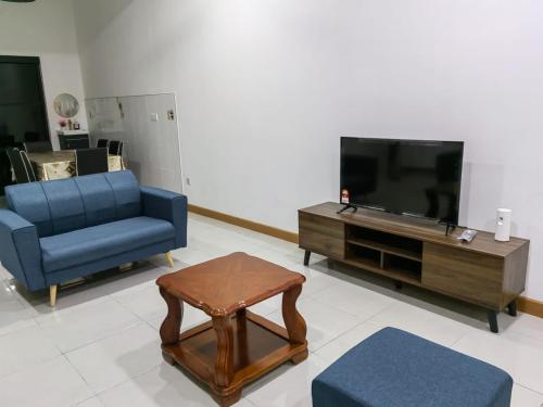 sala de estar con sofá azul y TV en SUNNY HOMESTAY KUALA SELANGOR en Kuala Selangor