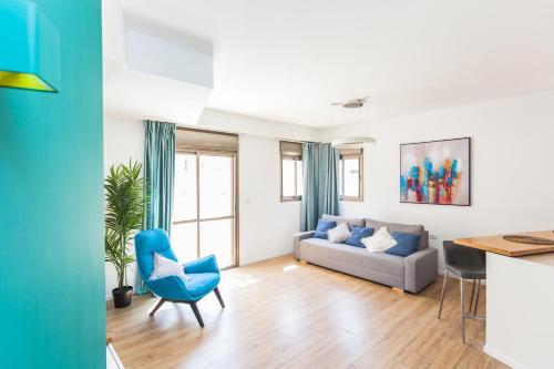 ein Wohnzimmer mit einem blauen Stuhl und einem Sofa in der Unterkunft One Step from the Sea. Apartment 5 +parking. in Tel Aviv