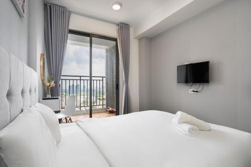 1 dormitorio con cama blanca y ventana grande en Awesome Tracy's Apartment, en Ho Chi Minh