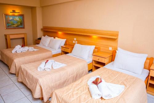 a hotel room with three beds with towels on them at THEMIS BEACH in Paralia Katerinis