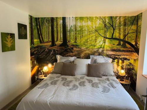 sypialnia z dużym łóżkiem z leśnym malowidłem w obiekcie Relaxing cottage bain nordique w mieście Ancinnes