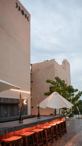 a row of tables with an umbrella and a building at Eterna Tulum in Tulum
