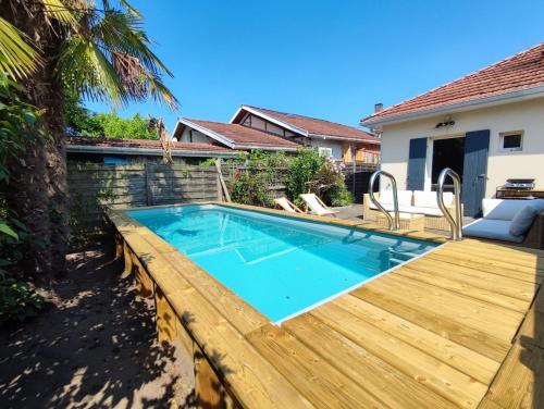 a swimming pool with a wooden deck next to a house at Maison de ville 6 couchages au centre de Lège bourg in Lège-Cap-Ferret