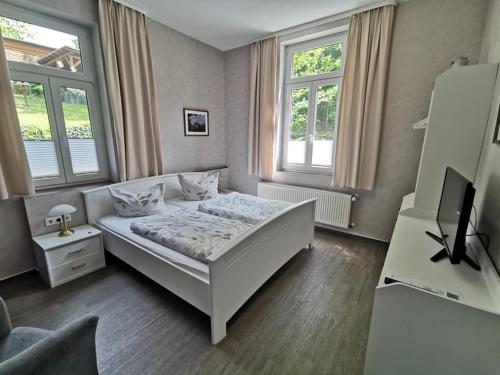 um quarto com uma cama branca e 2 janelas em Pension Ginko em Wernigerode
