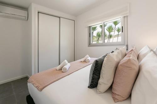 a bedroom with a white bed with pillows and a window at Nazaré Seashell House in Nazaré