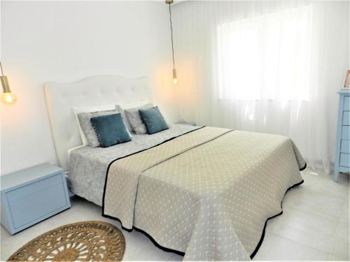 een witte slaapkamer met een groot bed met blauwe kussens bij Carvoeiro Boutique Apartment in Carvoeiro