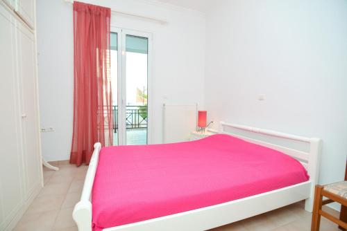 a bedroom with a white bed with a pink blanket at Kefalonia, Lixouri family friendly house & parking in Lixouri