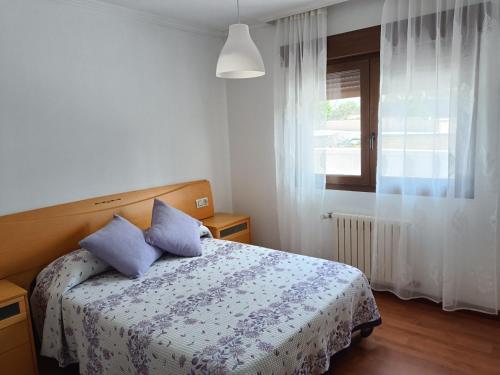 Un dormitorio con una cama con almohadas azules y una ventana en Casa/chalet en Sanxenxo 3hab., en Sanxenxo