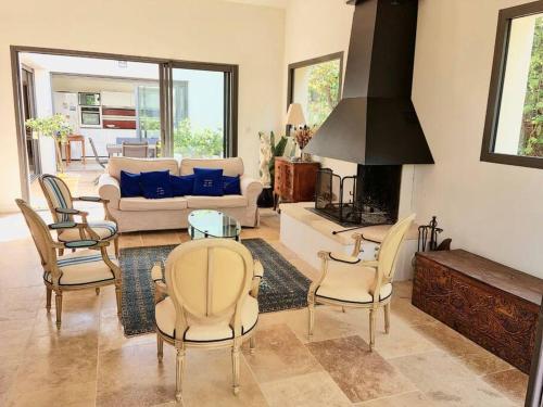 ein Wohnzimmer mit einem Sofa, einem Tisch und Stühlen in der Unterkunft Spacieuse villa, environs 10 min à pied des plages in La Garde