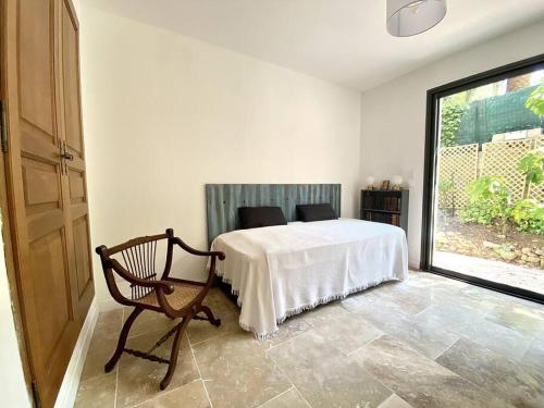 ein Schlafzimmer mit einem Bett, einem Stuhl und einem Fenster in der Unterkunft Spacieuse villa, environs 10 min à pied des plages in La Garde