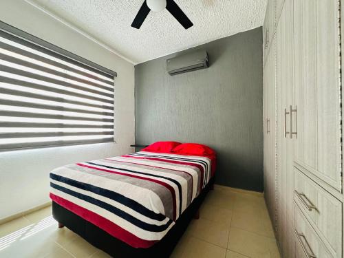 1 dormitorio con 1 cama con manta a rayas en Depa Xcalacoco, Playa Del Carmen en Playa del Carmen