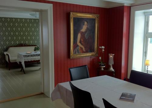 a dining room with a table and a painting on the wall at Hotel Kong Carl - Unike Hoteller in Sandefjord
