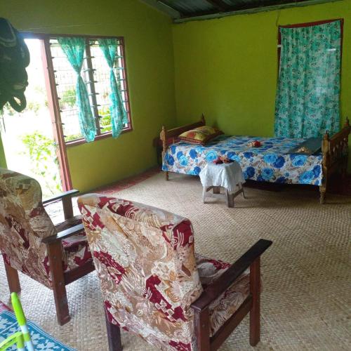 a bedroom with a bed and a couch and chairs at Yasawa Homestays in Nacula Island
