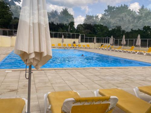 - une piscine avec des chaises et un parasol en face de celle-ci dans l'établissement Village Le Chat, à Écuras