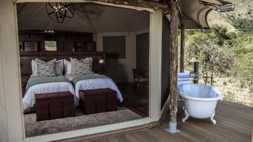 a bedroom with a tub and a bed with a window at Nkomazi Game Reserve by NEWMARK in Badplaas