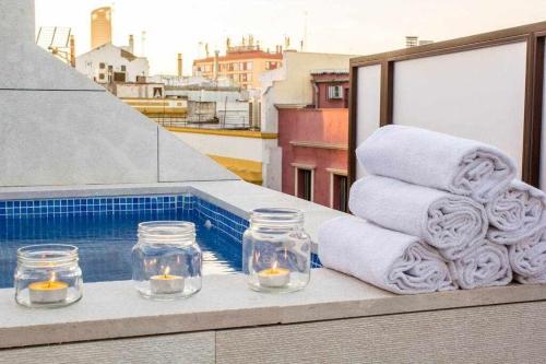 セビリアにあるÁtico con piscina junto catedral de Sevillaのバルコニーにタオルとキャンドルを用意しています。