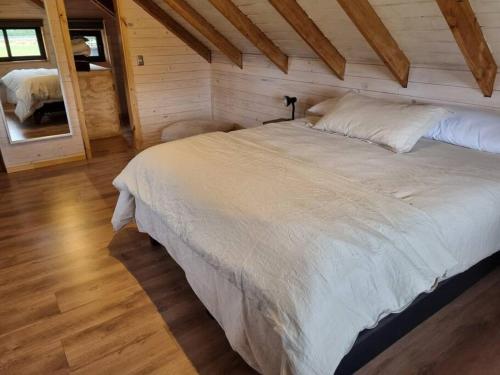 a bedroom with a large white bed in a cabin at Espectacular casa en Frutillar in Frutillar