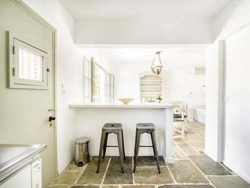 埃雷特里亞的住宿－MARVELOUS BEACH HOUSE，一间白色的厨房,在柜台上摆放着两张凳子