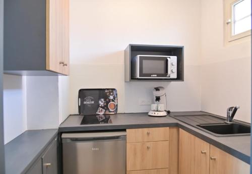 una piccola cucina con lavandino e forno a microonde di MOTEL ASCOT - Hotel & Appartements a Cagnes-sur-Mer