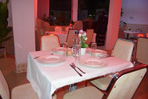 una mesa con un mantel blanco, platos y cubiertos en Hotel Berges du Sine, en Fatick