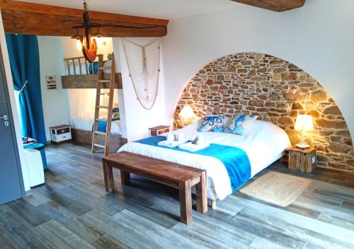 a bedroom with a bed and a stone wall at La Synchronicité - Chambres d'Hôtes in Vaudrimesnil