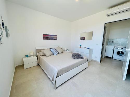 1 dormitorio blanco con 1 cama y lavadora en Atmosfere di mare, en Marina di Ragusa
