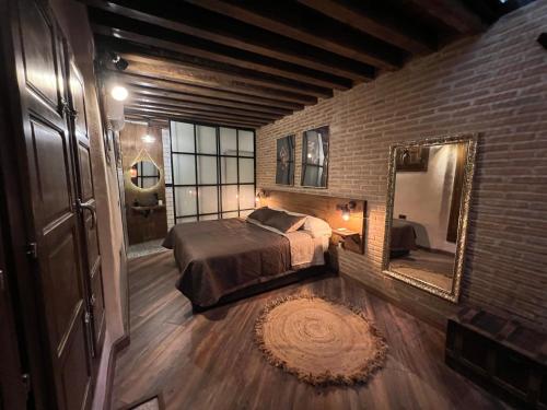 a bedroom with a bed and a mirror and a brick wall at Mirador Virgen de Gracia in Toledo