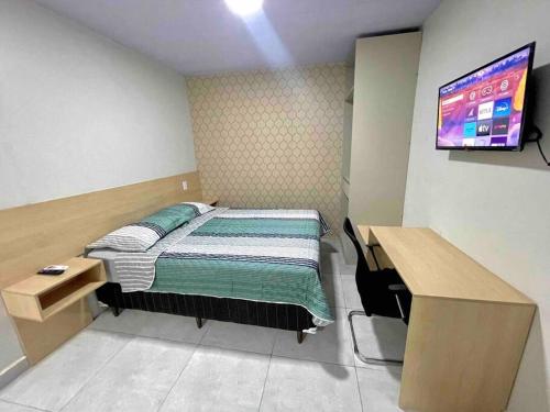 Schlafzimmer mit einem Bett, einem Schreibtisch und einem TV in der Unterkunft Apartamento Studio Centro in Macapá