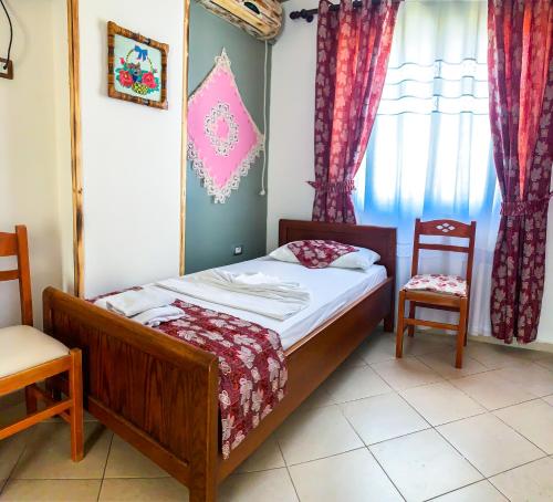 a small bedroom with a bed and two chairs at Oda`s Room in Sarandë