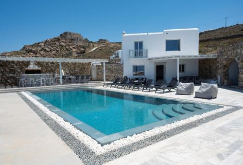 a villa with a swimming pool in front of a house at Villa Orion Mykonos - Magnificent Sea View in Mikonos