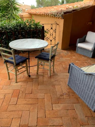 um pátio com uma mesa e cadeiras num pátio de tijolos em L'Olivastro em Porto Cervo