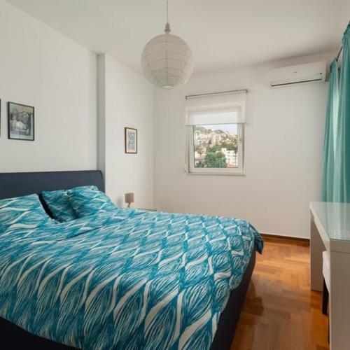 a bedroom with a bed with a blue comforter and a window at Panoramic Bliss in Herceg Novi in Herceg-Novi