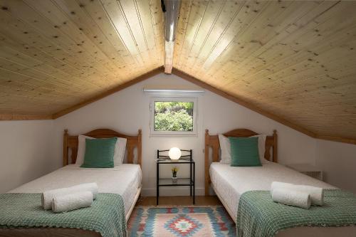 two beds in a attic room with a window at Porto Moniz Villa in Porto Moniz