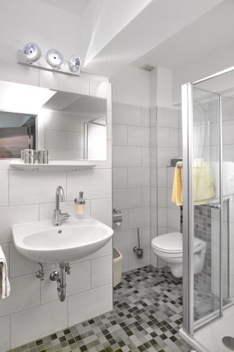 a white bathroom with a sink and a toilet at Weinhaus Henerichs in Pommern